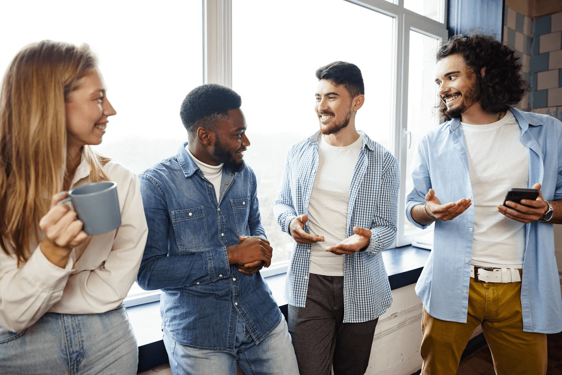Cheerful young business people having a talk during coffee break in office